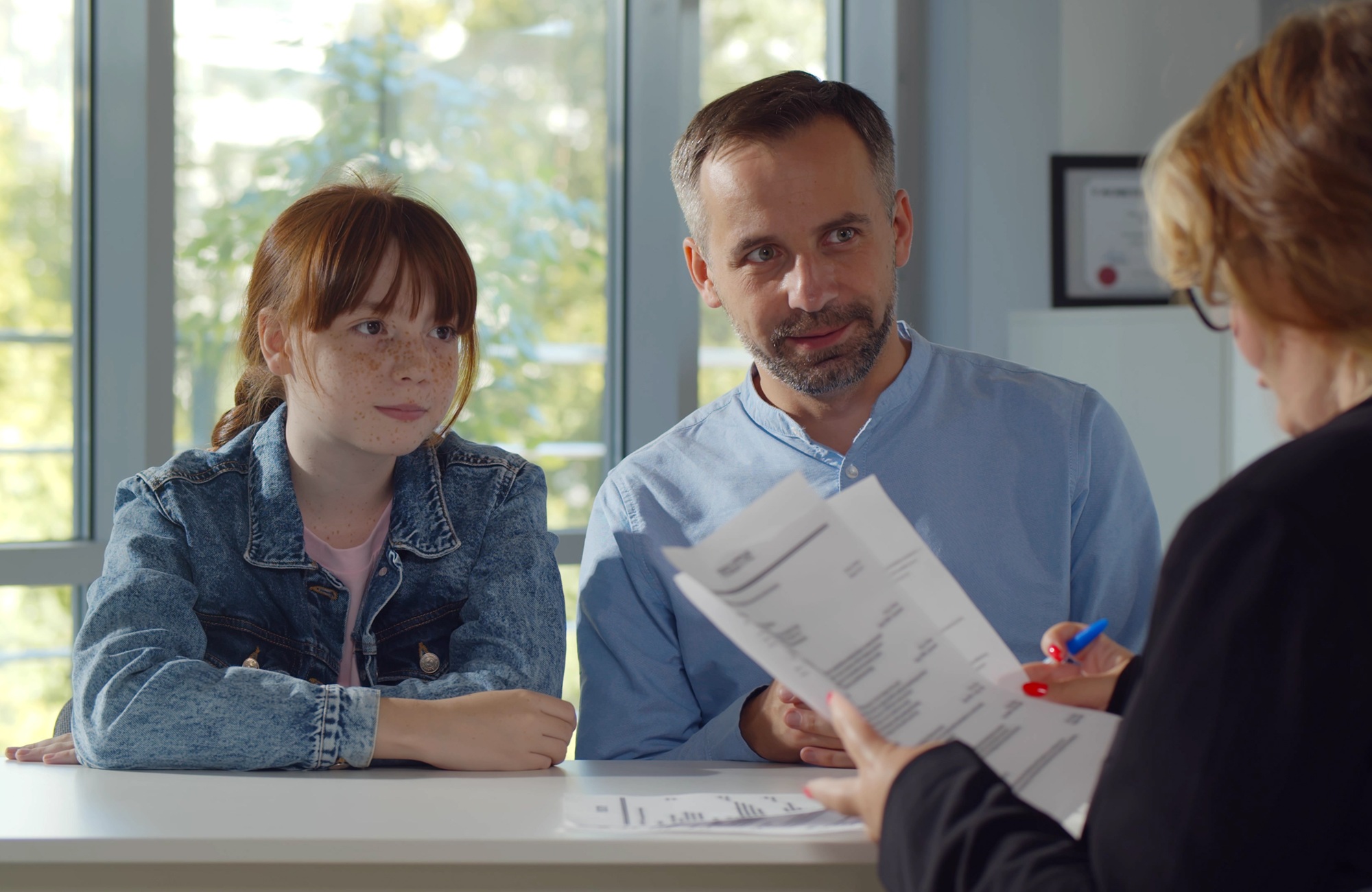 In and beyond the school day-Expanding access to the behavioral supports that shape young people’s futures_feature2: young red haired girl and father meet with education professional
