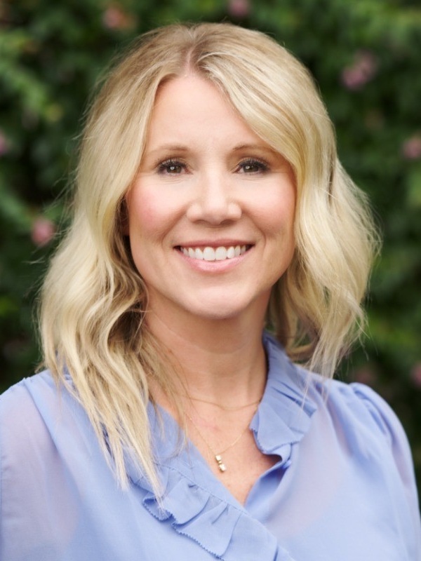 Kami Bible headshot: white woman with long blonde hair smiling and wearing light blue shirt outdoors