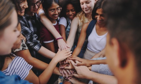thriving youth, no youth thrives alone_feature: group of diverse teens putting hands together in group