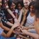 thriving youth, no youth thrives alone_feature: group of diverse teens putting hands together in group