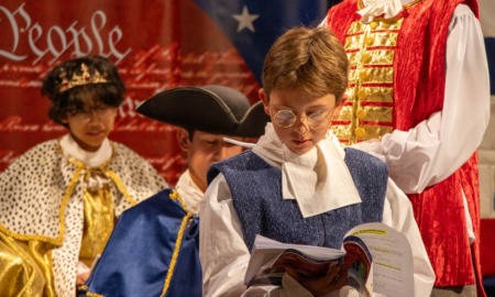 QA-As America turns 250, SPIRIT SERIES teaches democracy through theater_feature2: a young boy reads aloud during a performance in founding era garb