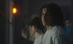 The boys we forgot to see-What working inside juvenile hall taught me about complex care_feature: young black teen standing in dark room in juvenile detention with other in background