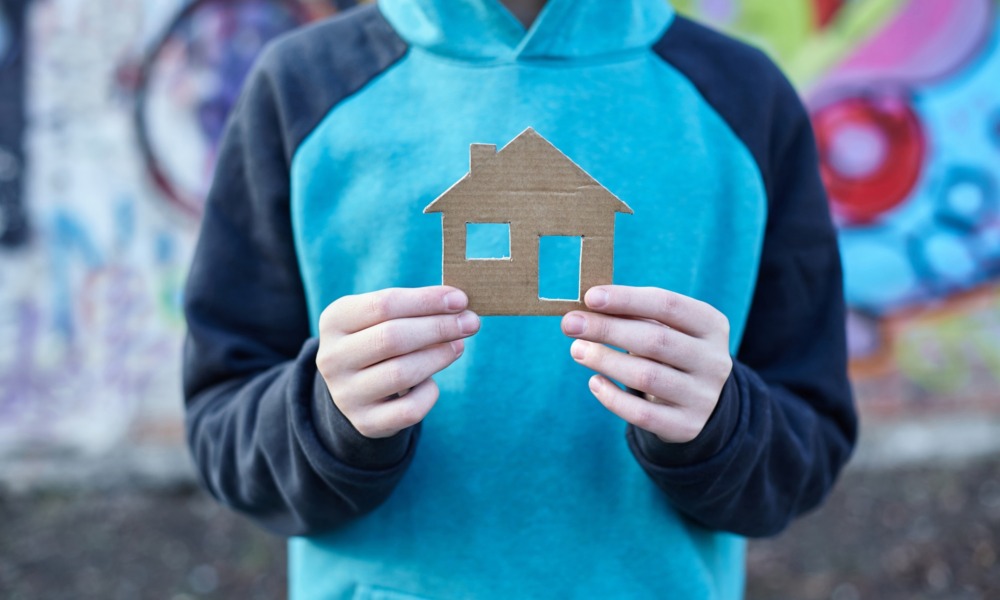 Youth homelessness prevention starts long before a young person loses their home_feature: photo of boy holding a cardboard cutout of a home