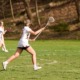 Youth lacrosse program grants_feature: teenage female lacrosse players and referee running across lacrosse field while playing