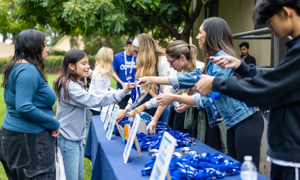 Addressing the opportunity cost of youth programs_feature: youth workers handing out things at table at event, youth opportunity