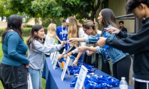 Addressing the opportunity cost of youth programs_feature: youth workers handing out things at table at event, youth opportunity