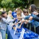 Addressing the opportunity cost of youth programs_feature: youth workers handing out things at table at event, youth opportunity