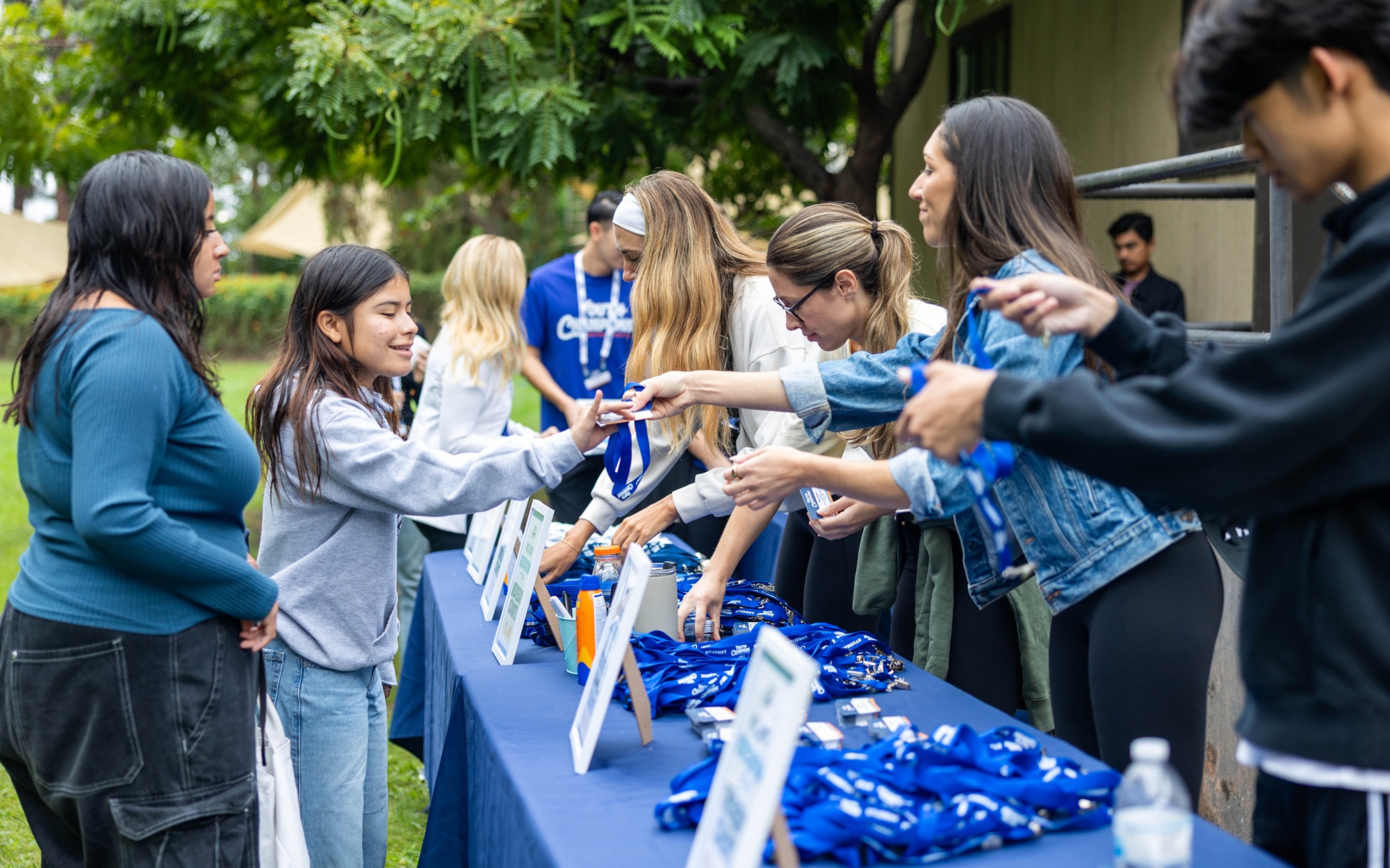 Addressing the opportunity cost of youth programs_feature: youth workers handing out things at table at event, youth opportunity