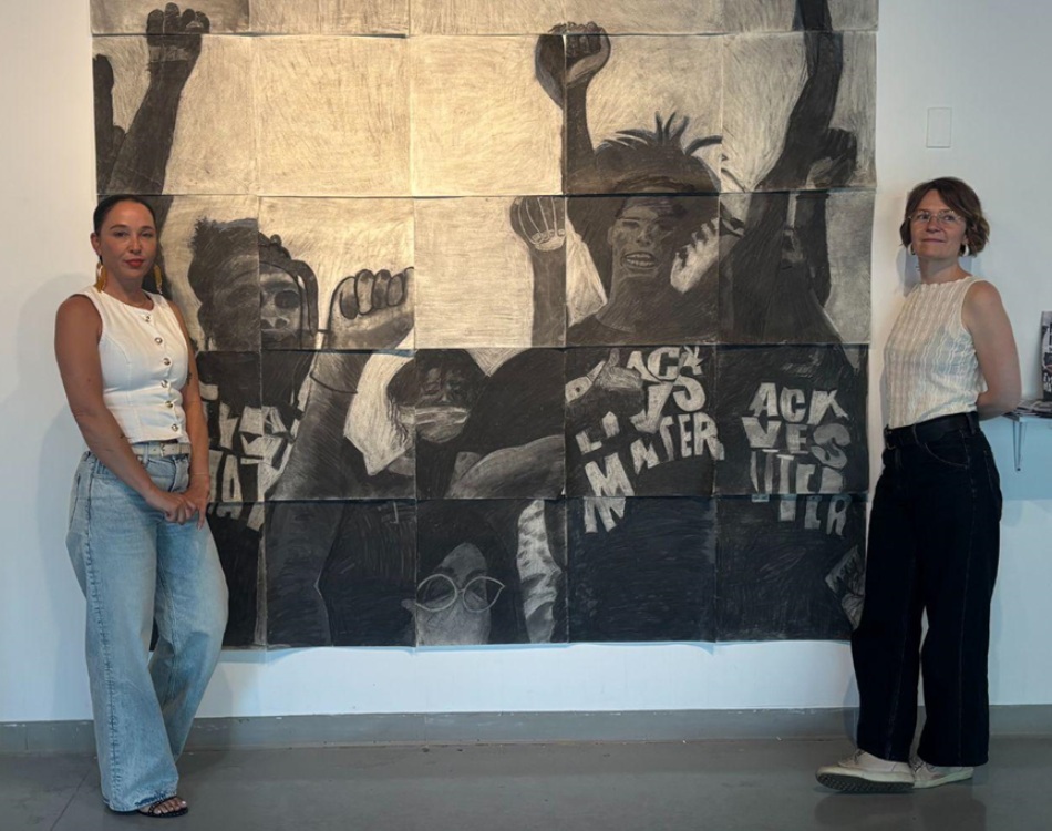 QA-Brit Christopher Gabriel Arika youth prisons don't work-magazine of youth perspectives building movement_exhibit photo: two women stand next to art piece at exhibit