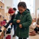 What 25 years of addressing clothing insecurity has taught us about helping children thrive_feature: a young black boy puts on a jacket at school