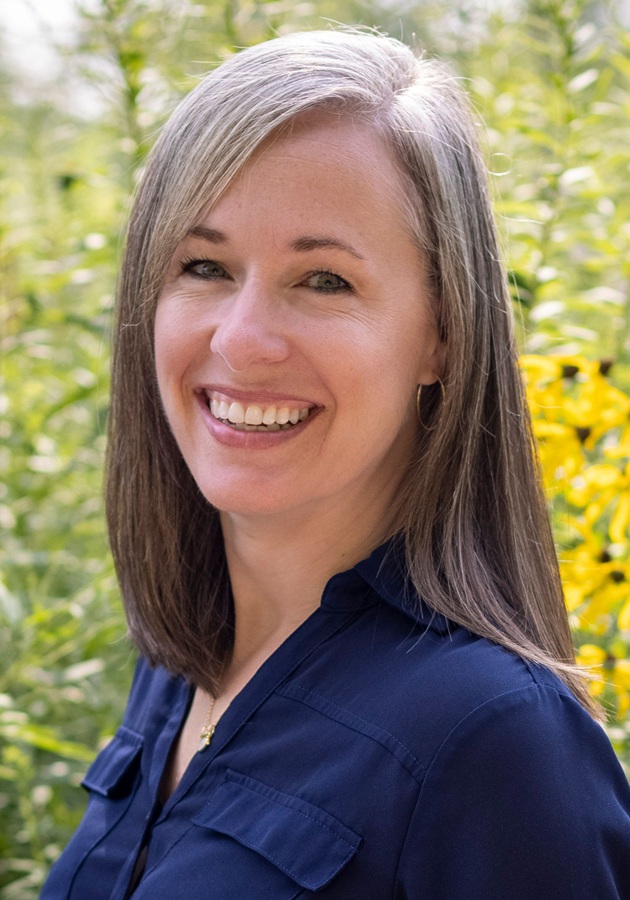 Deanna Moore headshot: white woman with shoulder length hair smiling outdoors wearing blue shirt