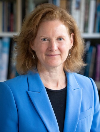 Lael E.H. Chester headshot: woman with medium-length red hair wearing blue blazer and black undershirt