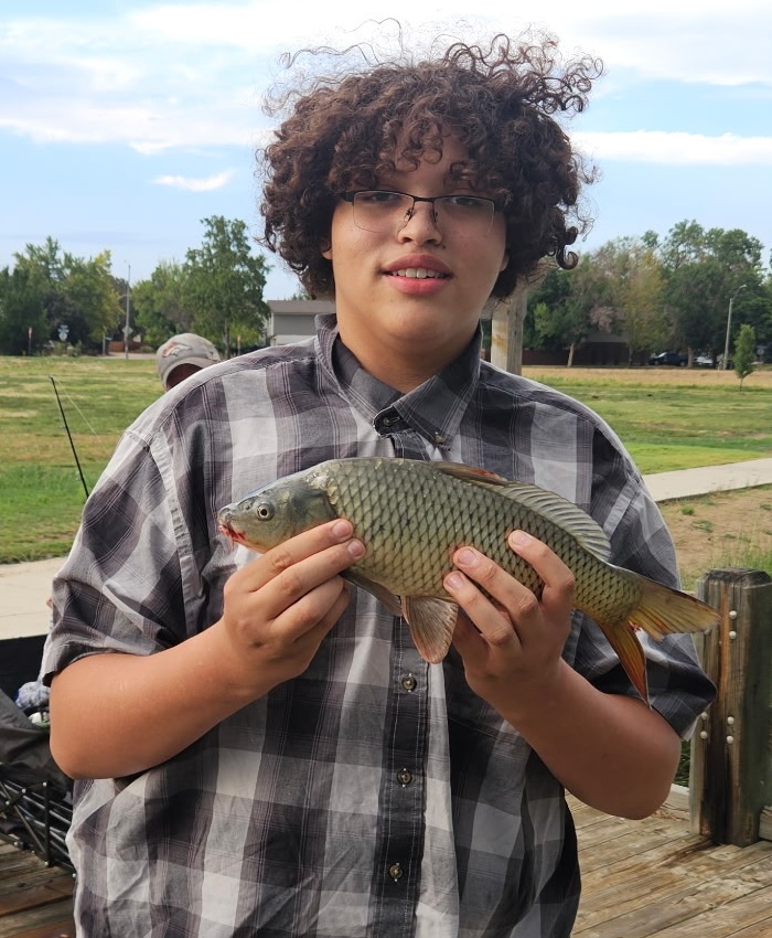 Mentorship for youth with disabilities should be a right, not a matter of chance_Anthony Velasquez: image of teen boy with culry hair holding a fish in outdoor setting