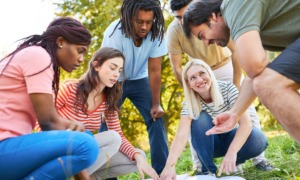 PD vibe check-Where professional learning meets care_feature: group of young staff outdoors pointing at papers on ground doing a team building exercise