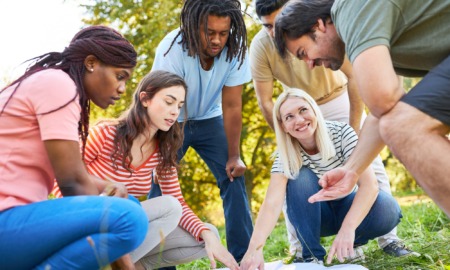 PD vibe check-Where professional learning meets care_feature: group of young staff outdoors pointing at papers on ground doing a team building exercise