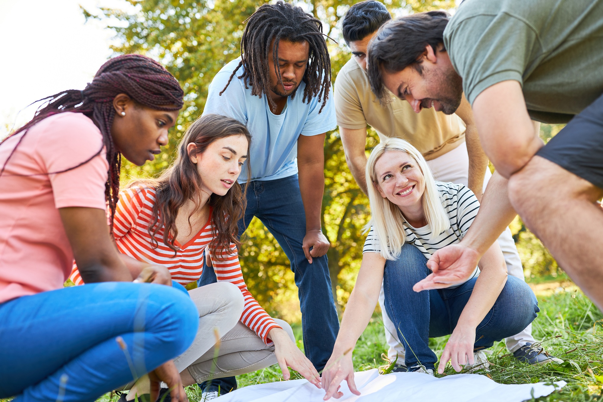 PD vibe check-Where professional learning meets care_feature: group of young staff outdoors pointing at papers on ground doing a team building exercise