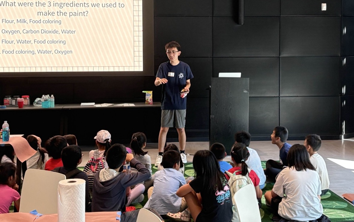 Students don’t just belong in STEAM classrooms-They belong at the front of them_feature: young Asian man stands at the front of a class full of young children teaching with powerpoint