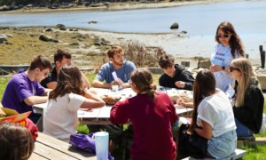 Young people need more than safer screens_feature: group of young people at table on coastline