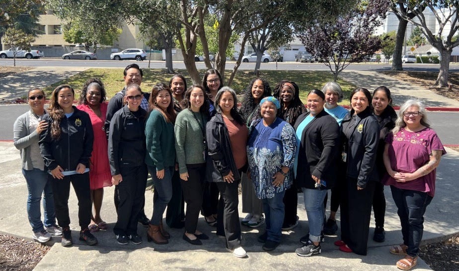 Badges and binders_Youth & Family Services Bureau group pic: group of people pose for a picture outdoors