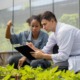 Food and agricultural sciences higher education improvement program grants: two agricultural students kneel in greenhouse looking at plants and tablet