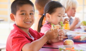 Out-of-school time OST youth development and food insecurity program grants: happy children eating at table outdoors