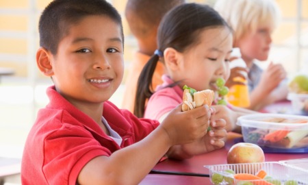 Out-of-school time OST youth development and food insecurity program grants: happy children eating at table outdoors