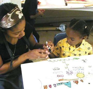 A woman shows a child how to draw and paint